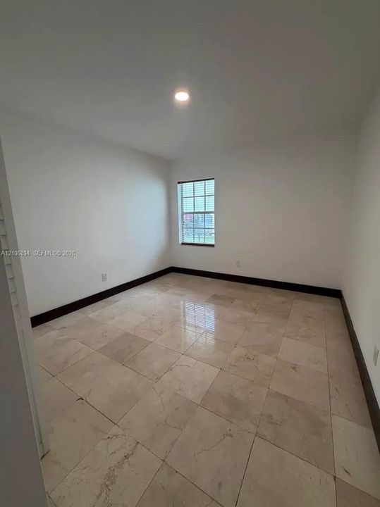 Neutral-toned stone tile flooring, single window with grid detailing, and recessed ceiling lighting