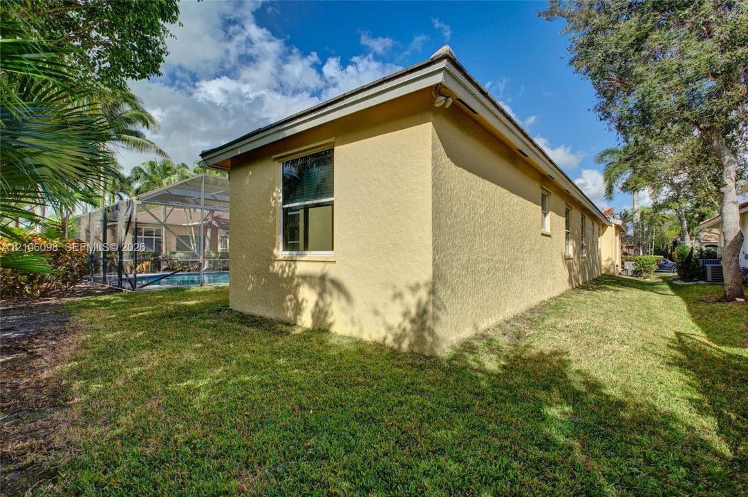 Stucco exterior, screened-in swimming pool enclosure, and mature landscaping
