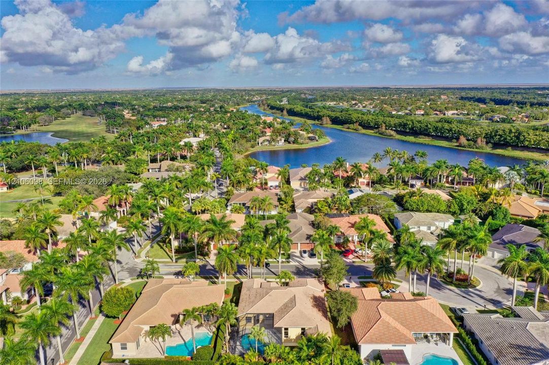 Aerial perspective featuring residential lots with private swimming pools, tile roofing, and mature tropical landscaping within a waterfront community