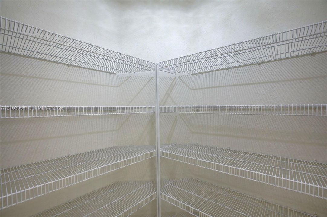 Corner storage area featuring white wire shelving across four tiers
