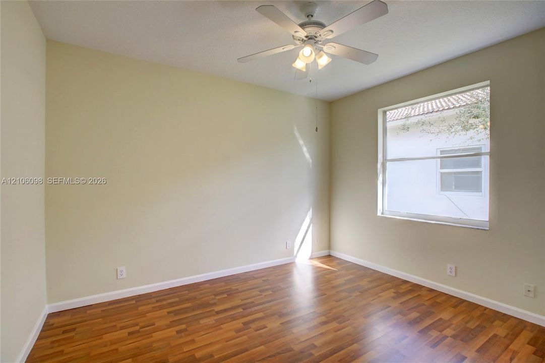 Interior room featuring wood-finish flooring, neutral wall paint, and a ceiling-mounted light fixture with a fan