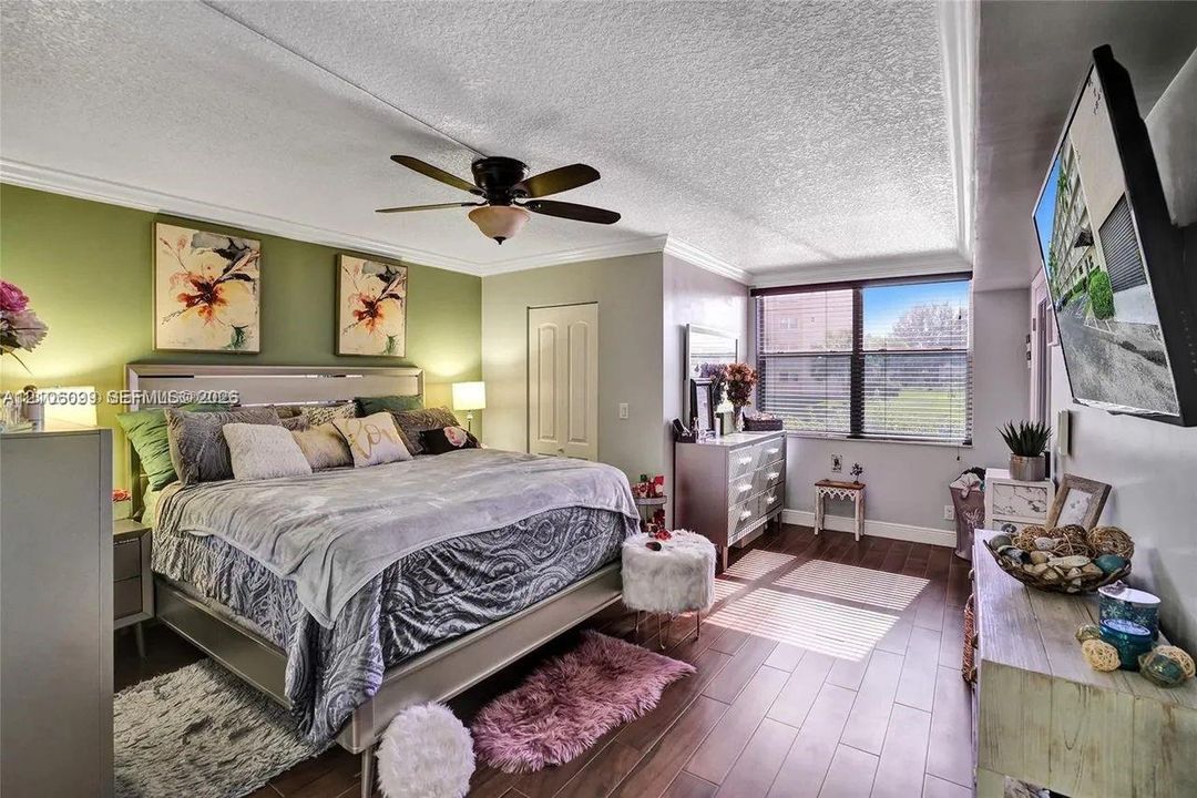 Wood-finish flooring, ceiling fan with integrated lighting, window with horizontal blinds, and paneled closet door