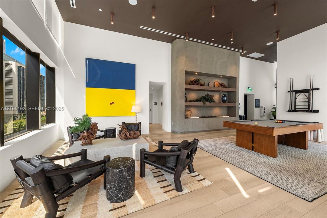 Contemporary open-concept living space showcasing soaring ceilings with recessed lighting, expansive wood-finish flooring, and abundant natural light from large windows