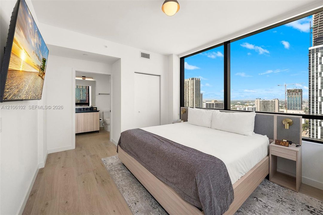 Floor-to-ceiling windows with urban skyline exposure, wood-finish flooring, and minimalist interior finishes