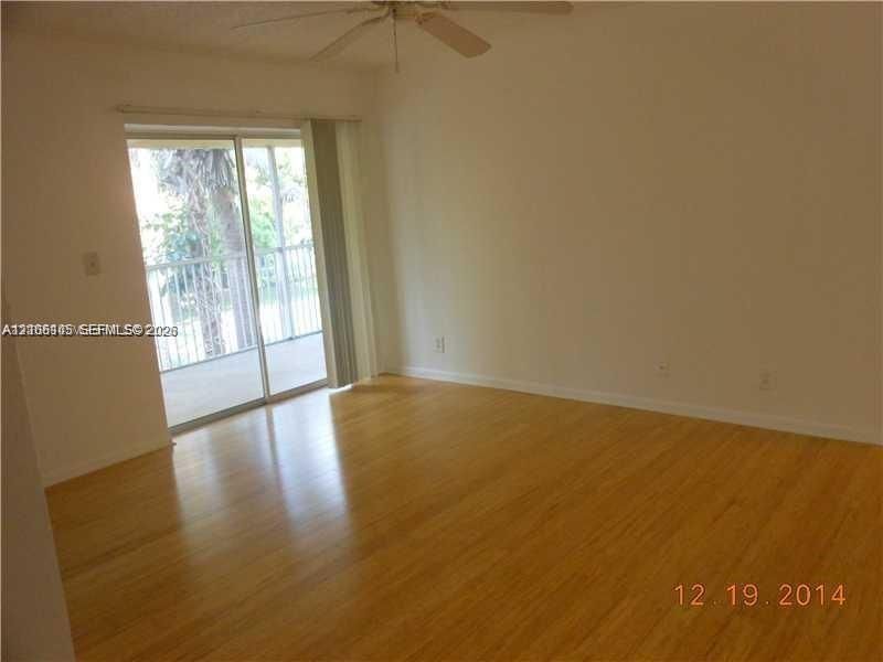 Wood-finish flooring, ceiling fan with light fixture, and sliding glass door with access to a railed balcony