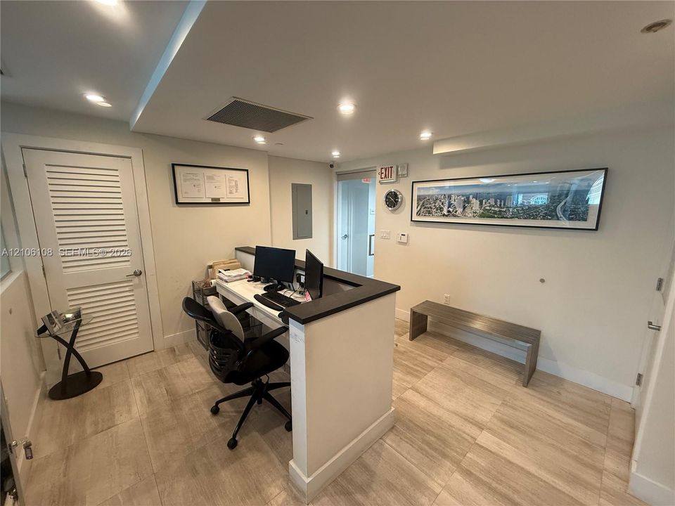 Custom built-in service counter with dark finish countertop, wood-finish tile flooring, recessed ceiling lighting, and louvered door entry