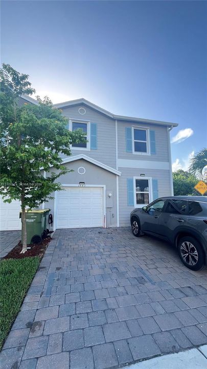 Two-story exterior featuring horizontal siding, decorative shutters, a single-car garage, and a paver driveway