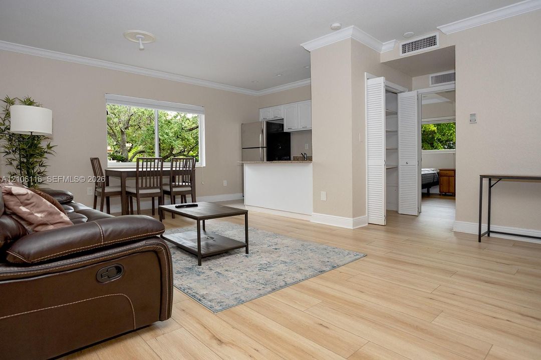 Light-filled interior featuring wood-finish flooring, crown molding, stainless steel kitchen appliances, and louvered-door closet cabinetry