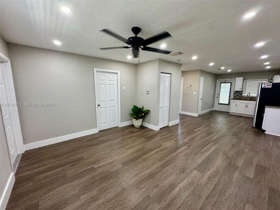 Open-concept interior featuring wood-finish flooring, recessed lighting, a ceiling fan, and white shaker-style cabinetry with neutral countertops