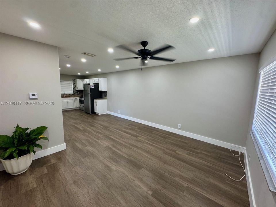 Open-concept interior featuring wood-finish flooring, recessed lighting, a matte black ceiling fan, and white cabinetry