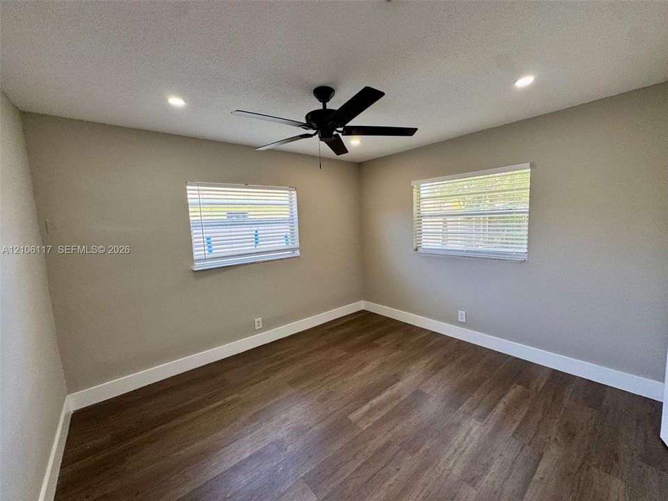 Neutral-toned room featuring wood-finish flooring, a matte black ceiling fan, and recessed lighting