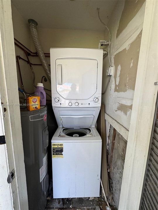 Stacked laundry unit with dryer and top-loading washer, accompanied by a dedicated water heater