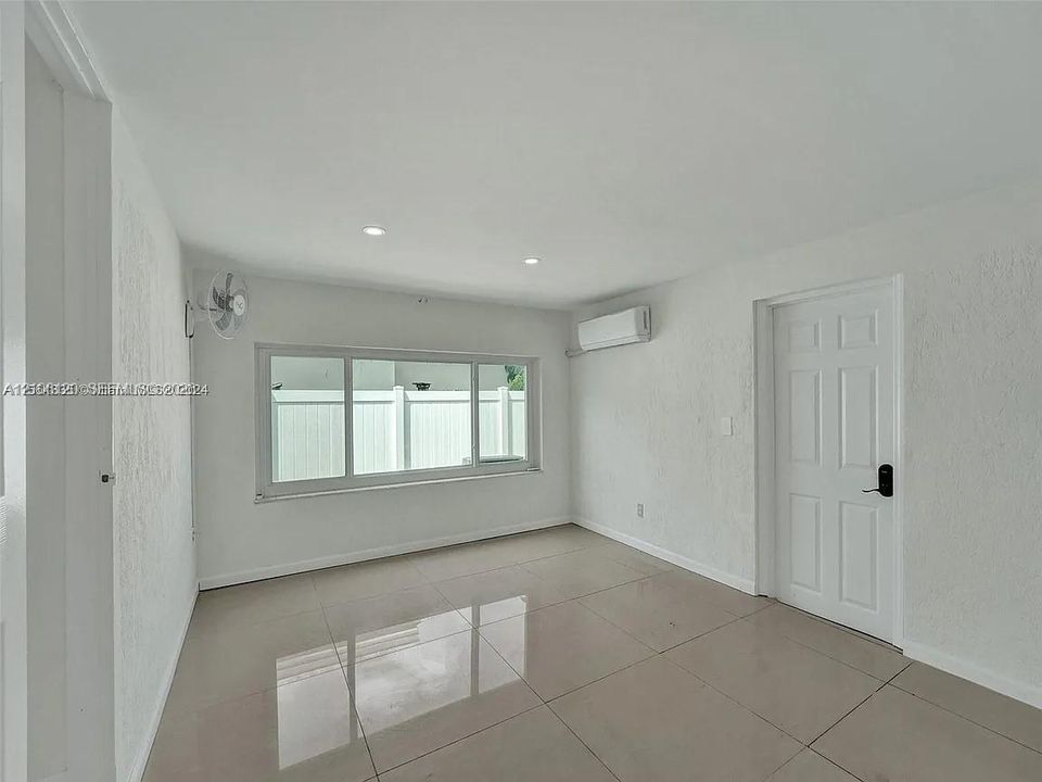 Interior space featuring large-format tile flooring, recessed lighting, wall-mounted air conditioning unit, and expansive multi-pane window