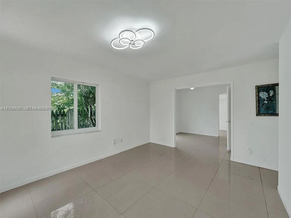 Neutral-toned large-format tile flooring, contemporary multi-ring LED flush-mount lighting, and a single-pane window with exterior greenery