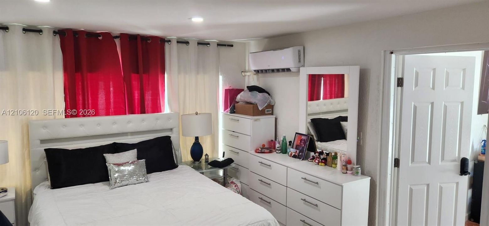 Recessed ceiling lighting, wall-mounted ductless climate control unit, and white six-panel interior door