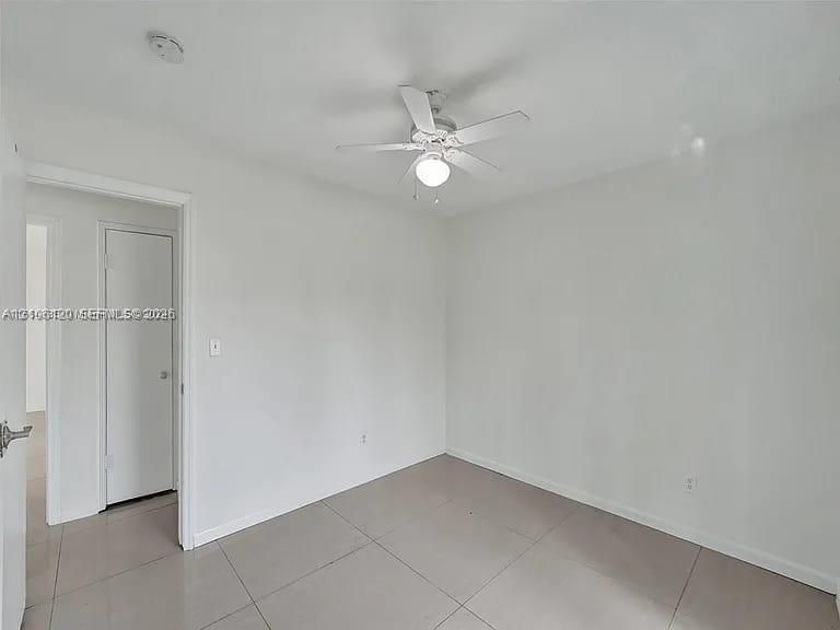 Neutral-toned large-format tile flooring and white ceiling-mounted fan with integrated light fixture