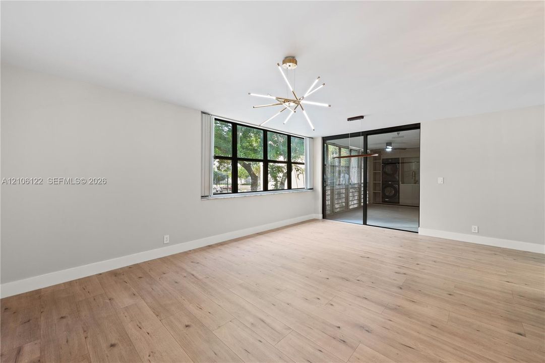 Open living area featuring wood-finish flooring, a modern sputnik-style chandelier, expansive multi-pane windows, and black-framed sliding glass doors