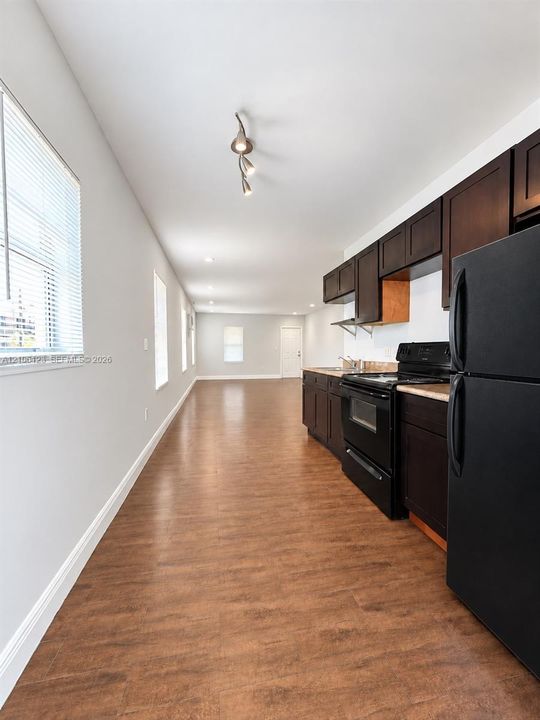 Kitchen featuring dark cabinetry, black built-in appliances, wood-finish flooring, recessed ceiling lighting, and multiple windows