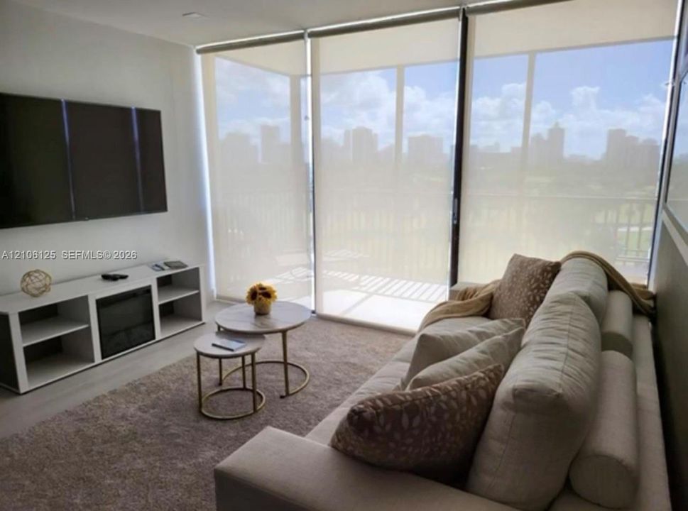 Floor-to-ceiling windows with integrated roller shades and neutral wall-to-wall wood-finish flooring