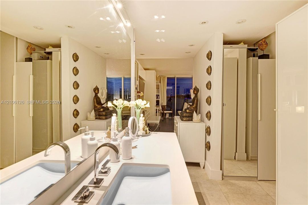 Dual-sink vanity with rectangular undermount basins, stone-finish countertop, polished chrome widespread faucets, and large-format wall-to-wall mirror with recessed ceiling lighting