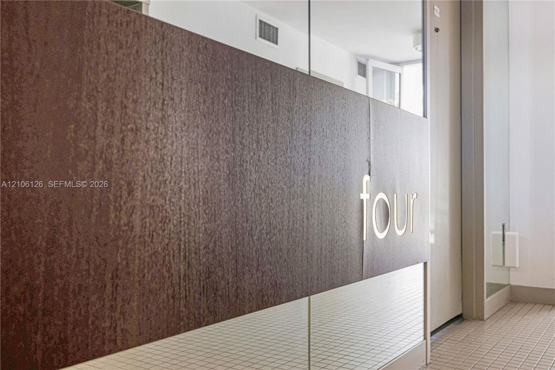 Textured dark bronze-finish paneling featuring metallic signage, accented by glass partitioning and light-toned floor tiling
