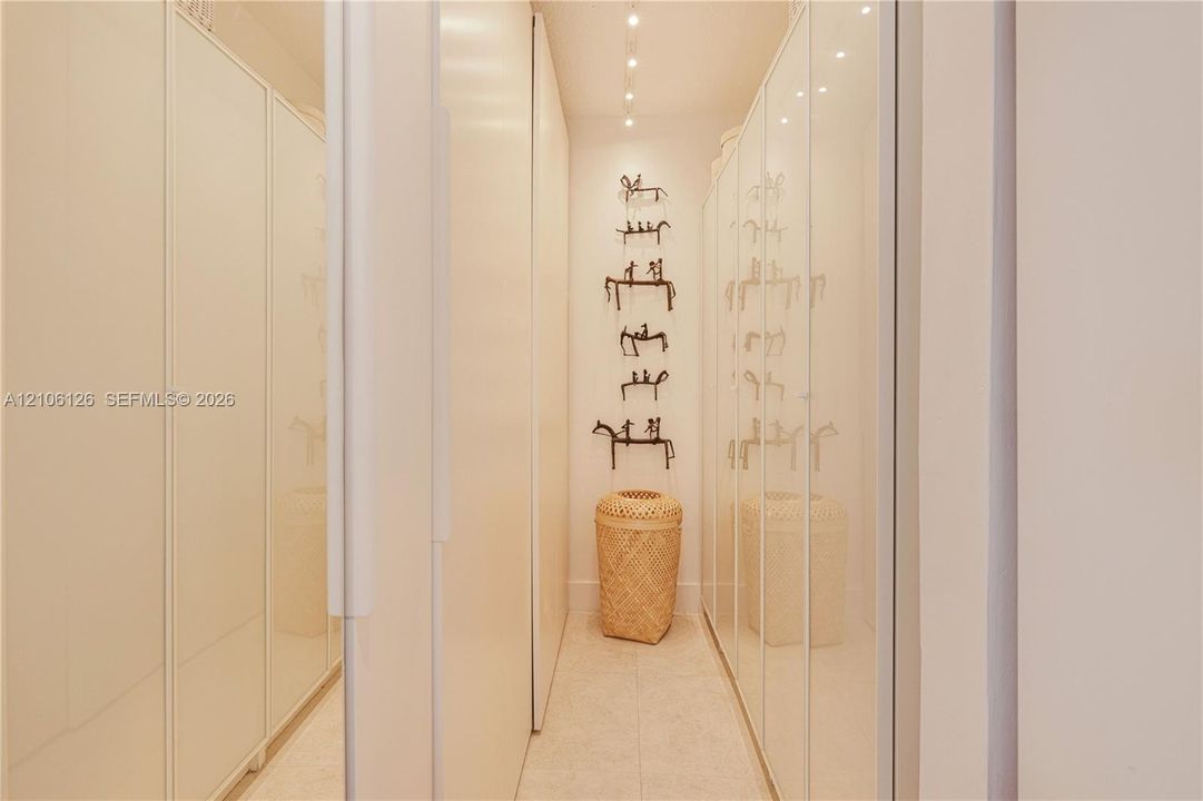 Full-height cabinetry with high-gloss white finish, recessed ceiling track lighting, and neutral stone-finish flooring