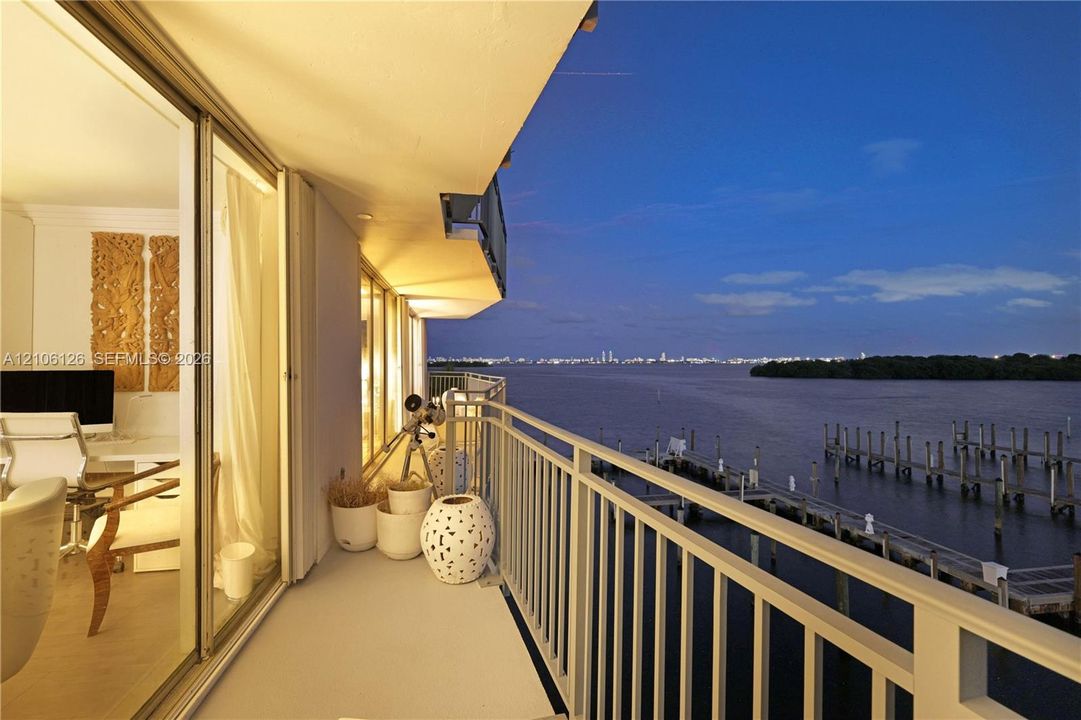 Private balcony featuring a metal railing, floor-to-ceiling glass sliding doors, and waterfront scenery