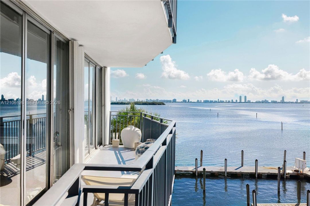 Covered balcony featuring full-height glass sliding doors, metal railings, and direct water frontage