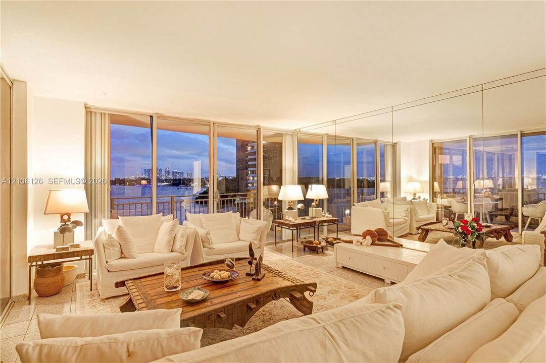 Living area featuring expansive floor-to-ceiling glass sliding doors, polished stone flooring, and a floor-to-ceiling mirrored wall