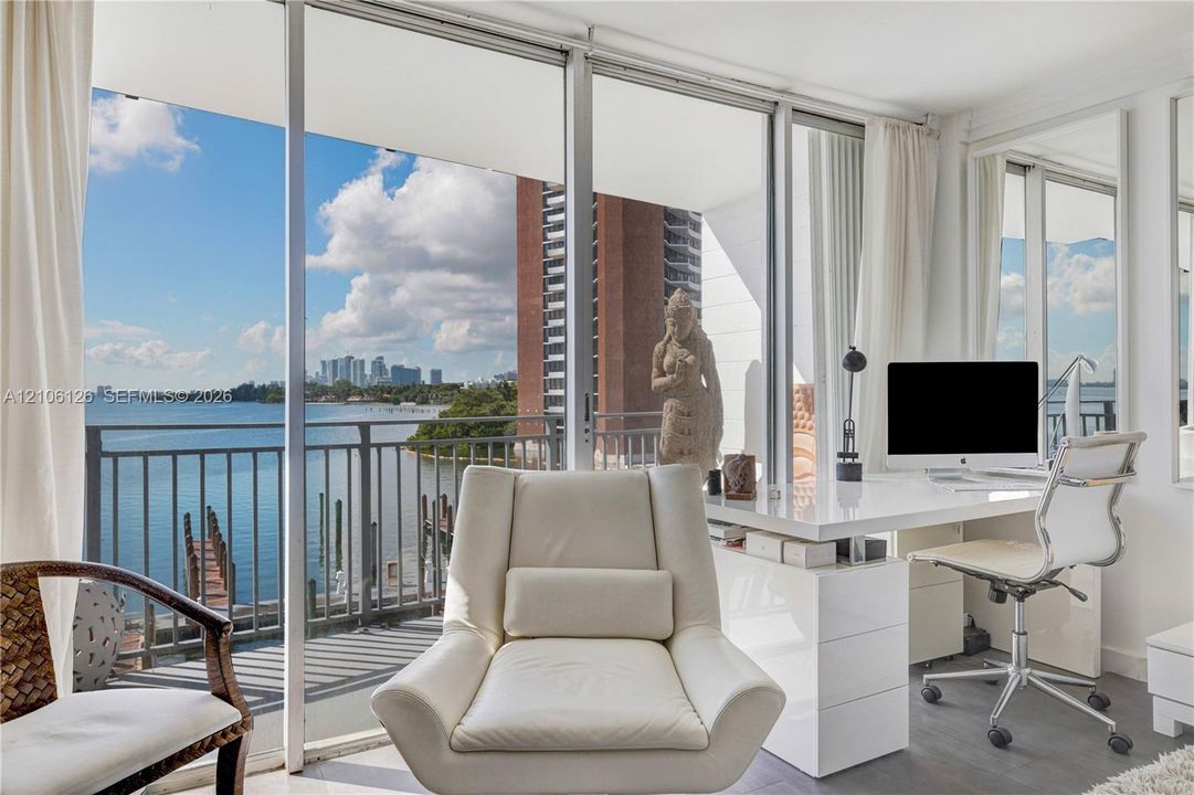 Floor-to-ceiling glass sliding doors, private balcony with metal railing, and water scenery