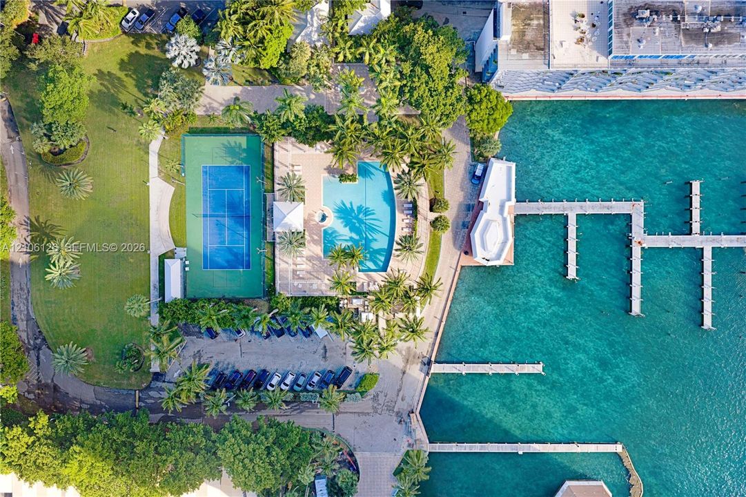 Waterfront property featuring a private marina with multiple boat slips, a swimming pool, a tennis court, and expansive landscaped grounds