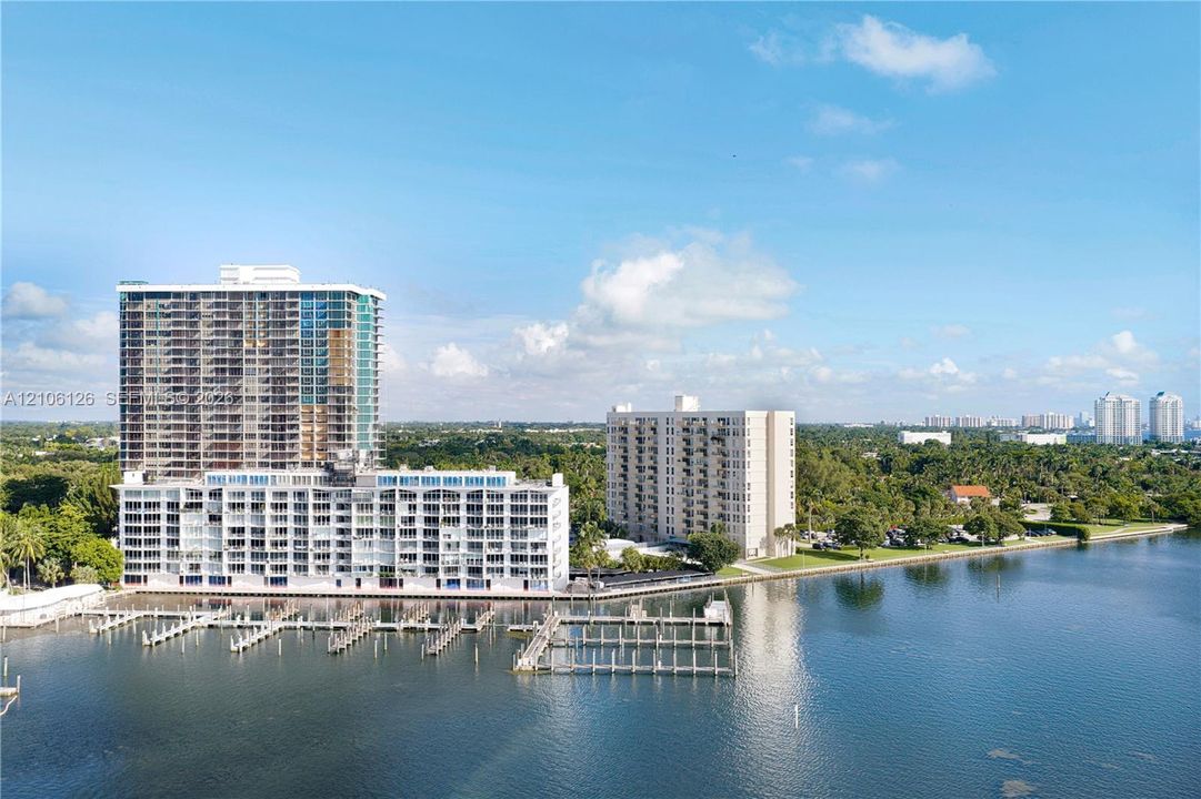 High-rise residential building featuring expansive water frontage, deep-water boat slips, and mature coastal vegetation