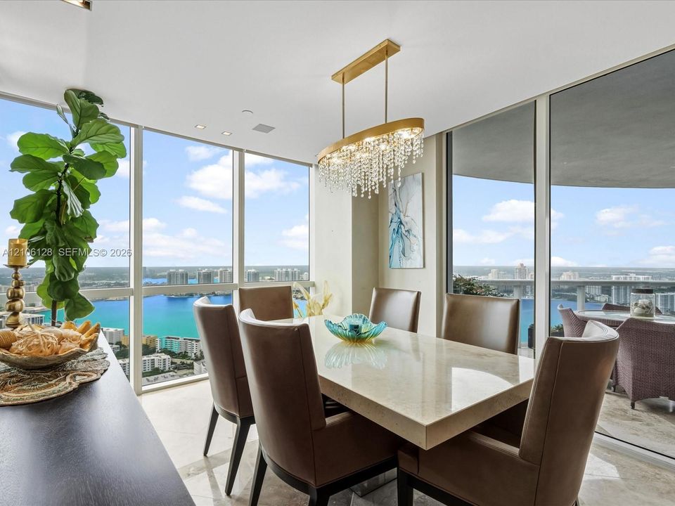 Floor-to-ceiling windows, crystal chandelier, and light-toned flooring featuring a expansive balcony and panoramic water exposure