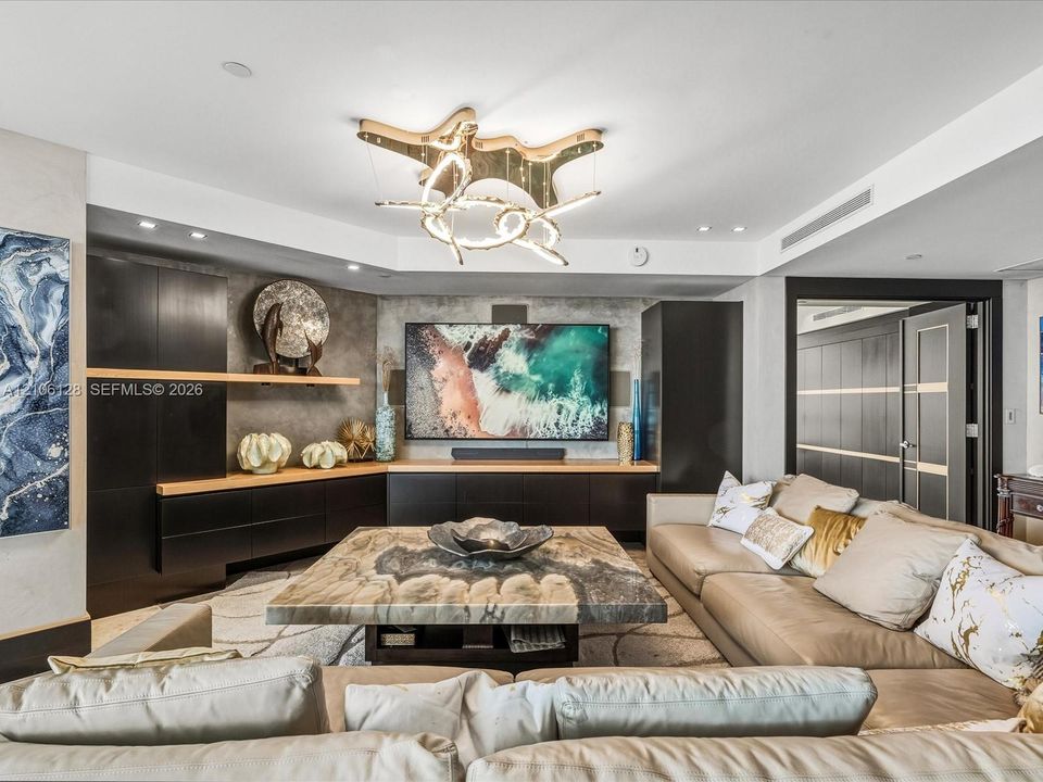 Custom built-in dark cabinetry with integrated shelving, stone-finish feature wall, and sculptural modern chandelier