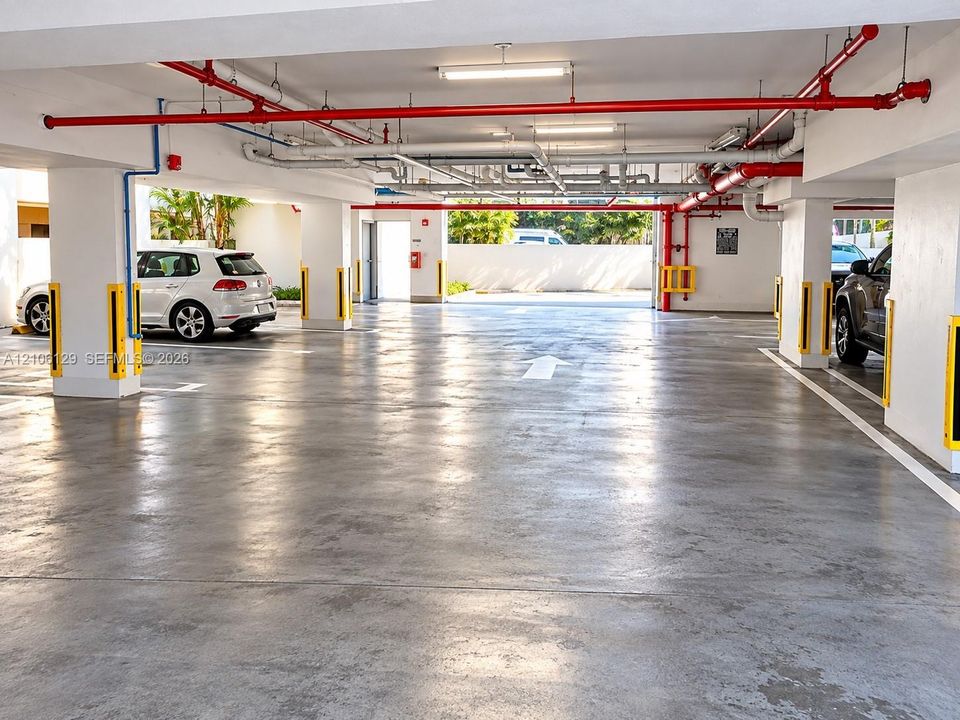 Covered parking garage featuring smooth concrete flooring, structural concrete support columns, and overhead fluorescent lighting