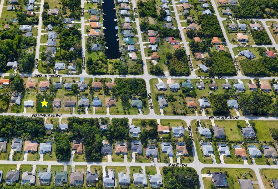 Aerial perspective of a corner lot featuring mature trees, a rectangular parcel footprint, and established residential street infrastructure