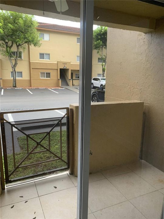 Covered patio featuring ceramic tile flooring, solid masonry partition walls, and a metal-frame enclosure