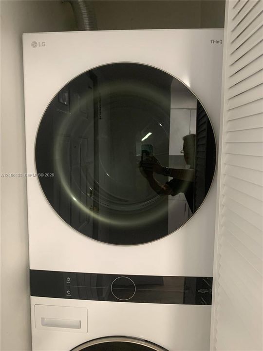 Stacked white front-loading laundry unit with integrated digital control panel and circular tempered glass door