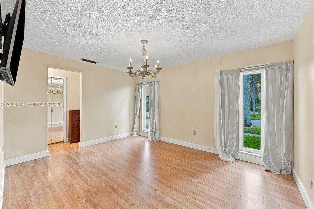 Wood-finish flooring, multi-light chandelier, and large windows providing exterior exposure