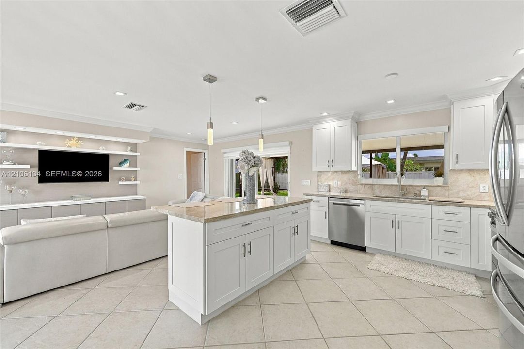 Kitchen featuring white cabinetry, center island with stone-finish countertop, stainless steel appliances, tile flooring, and integrated wall shelving