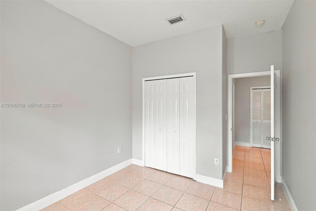 Neutral-toned interior space featuring light-colored tile flooring and white bi-fold closet doors