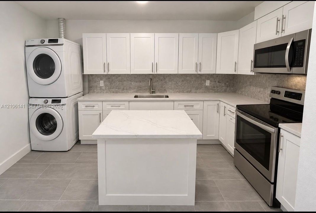 Kitchen featuring white shaker-style cabinetry, a central island with a solid surface countertop, stainless steel appliances, stone-look tile backsplash, and ceramic floor tiling