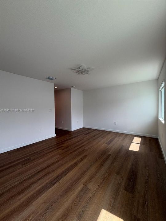 Interior space featuring wood-finish flooring, neutral walls, and a decorative flush-mount ceiling fixture