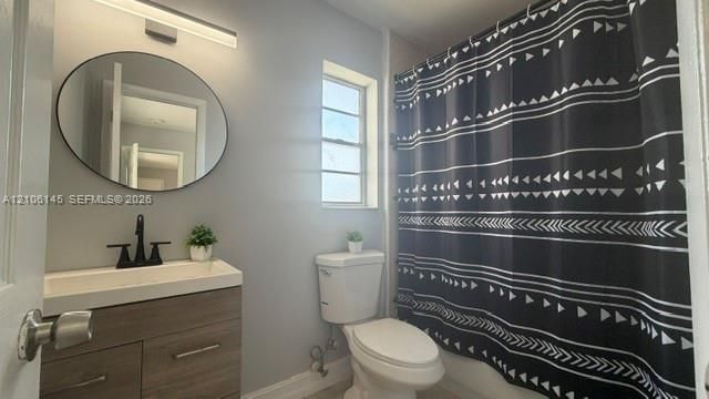 Bathroom featuring a wood-finish vanity with a rectangular sink, matte black widespread faucet, oval wall-mounted mirror, and linear LED lighting