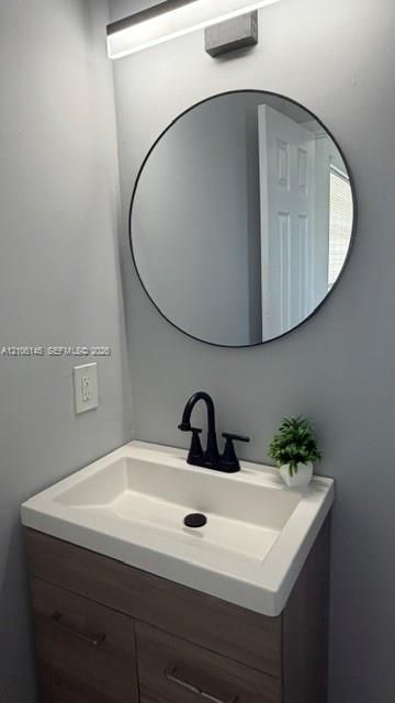 Wall-mounted vanity with a rectangular sink, matte black widespread faucet, circular mirror with a thin frame, and linear LED vanity light