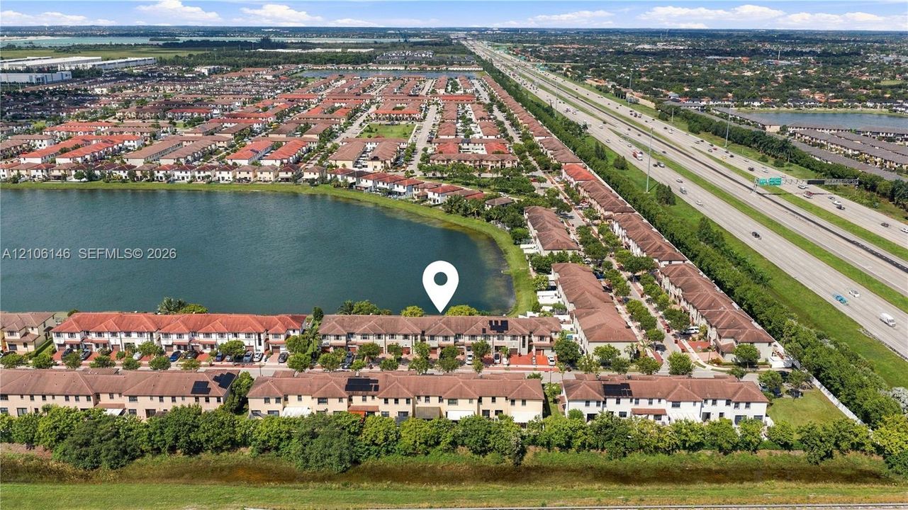 Aerial perspective of a multi-unit residential community situated along a waterfront with tile roofing and established perimeter landscaping