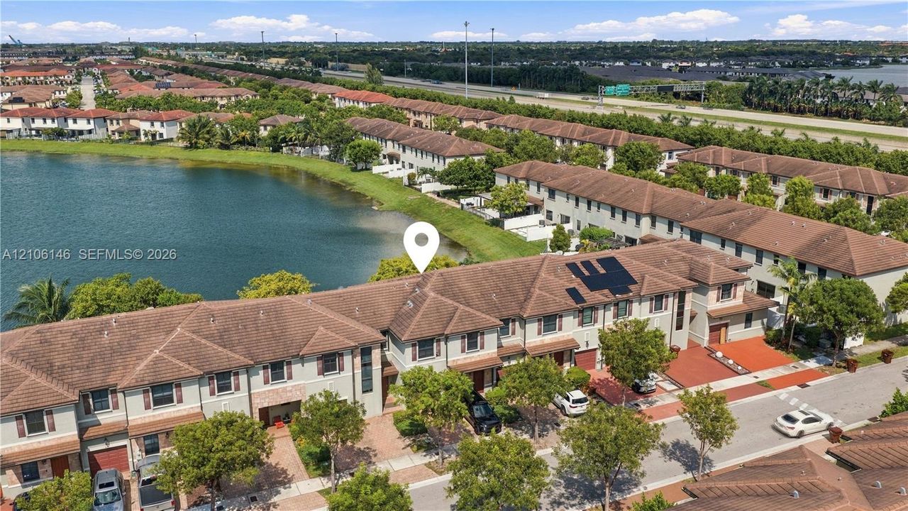 Multi-level townhome featuring a tiled roof, paver driveway, and waterfront positioning