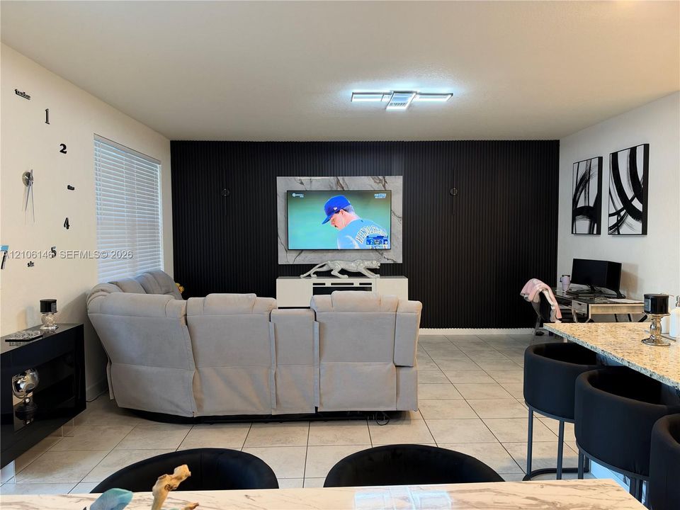 Accent wall featuring floor-to-ceiling vertical slats, stone-finish focal panel, large-format tile flooring, and integrated flush-mount ceiling lighting
