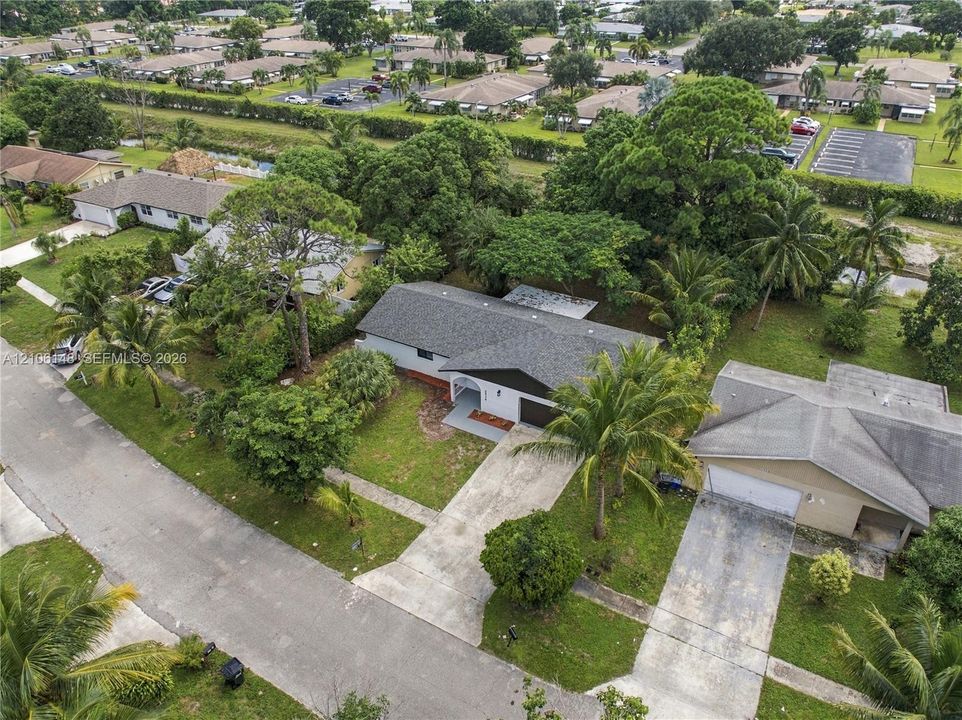 Aerial perspective of a single-story residence featuring a composite shingle roof, a concrete driveway, and mature landscaping