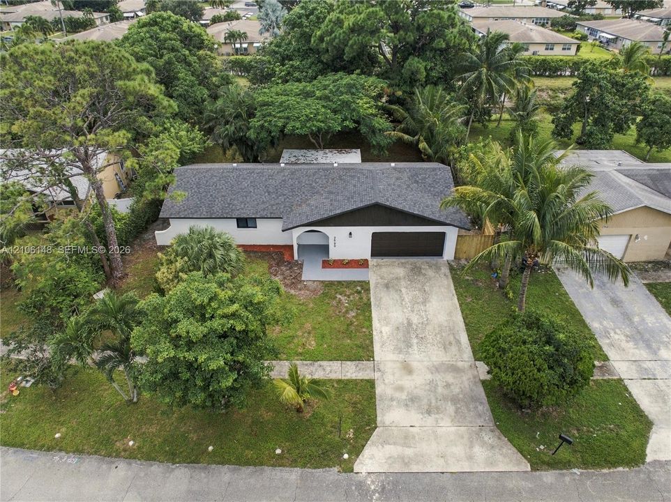 Single-story residence featuring an asphalt shingle roof, a two-car garage, an arched entryway, and a concrete driveway surrounded by mature landscaping